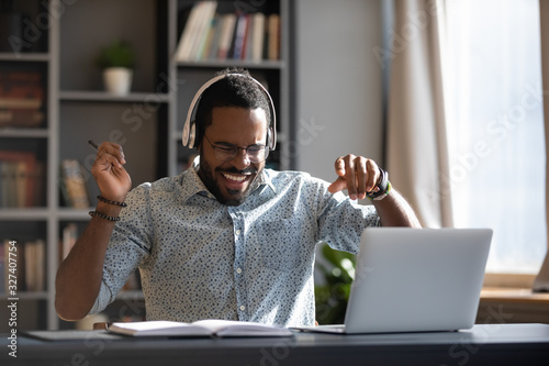 Happy young african american businessman enjoying listening energetic music. photo