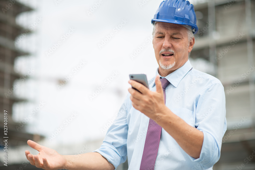 Angry and stressed architect looking at his mobile phone Angry and stressed architect looking at his mobile phone
