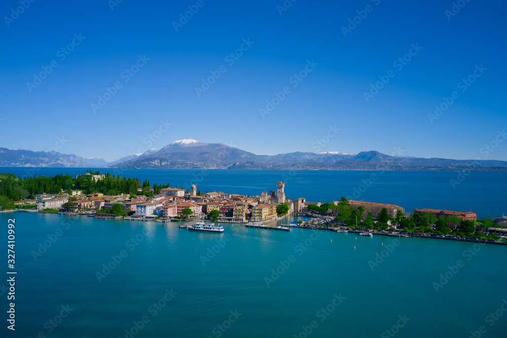 Sirmione island Lake Garda, Italy. The ship stands at the pier. Aerial view. Mountains and blue sky in the background.