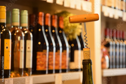 Wine bottles on wooden shelf in wine store and corks with corkscrew
