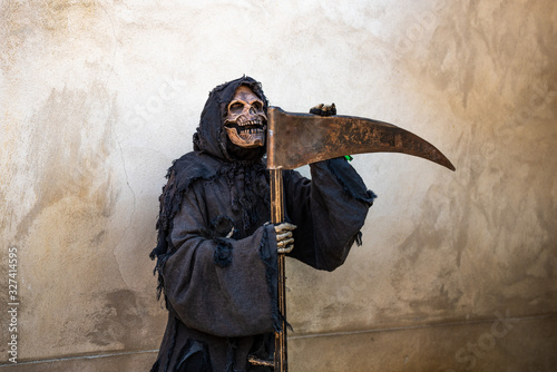 The Grim Reaper leaning against rusted scythe