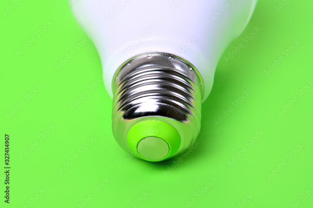 Green energy concept with a light bulb close up on a green background