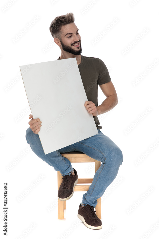 Cheerful casual man smiling and holding a blank billboard Cheerful casual man smiling and holding a blank billboard