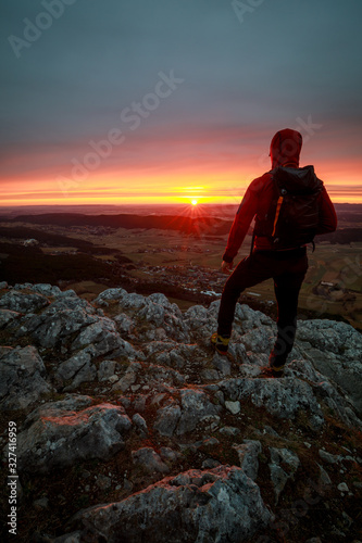 Fototapeta Naklejka Na Ścianę i Meble -  Hiker with backpack relaxing on top of a mountain and enjoying sunrise