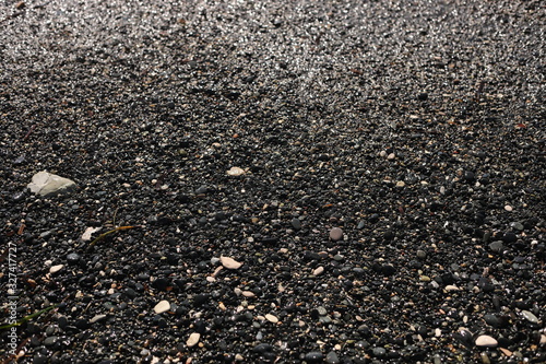 Shallow volcanic black sand beach and pebbles on the sea coast. Ocean shore natural background with copy space. selective focus
