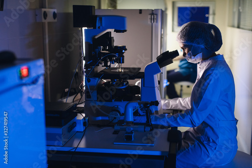 In a Modern Laboratory Scientist Conduct Experiments. The embryologist Examines Samples with a Microscope photo