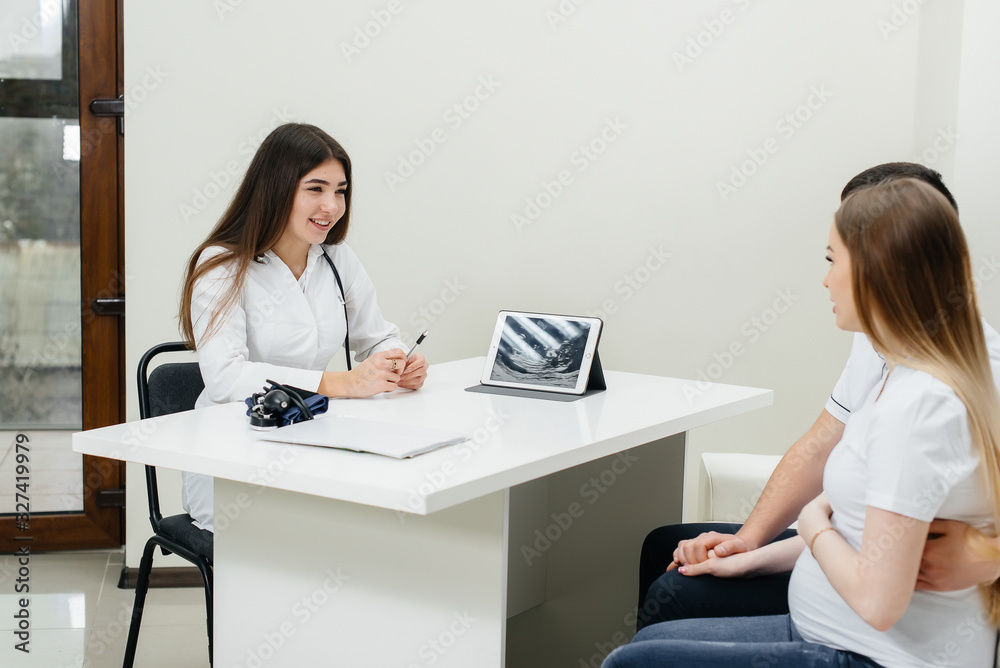 A young couple at a gynecologist's consultation after an ultrasound. Pregnancy, and health care A young couple at a gynecologist's consultation after an ultrasound. Pregnancy, and health care