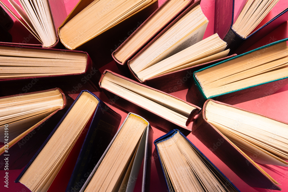 Fototapeta premium Many multi-colored books on a pink background.