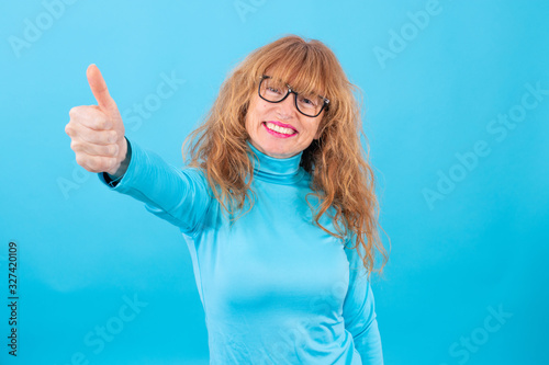 portrait of adult or senior woman with thumb raised in approval or okay