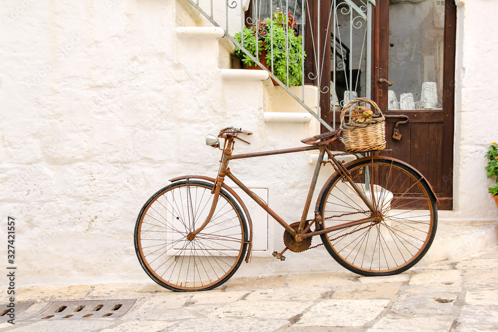 An old, rusty bike used as decoration with flower basket in front of a house