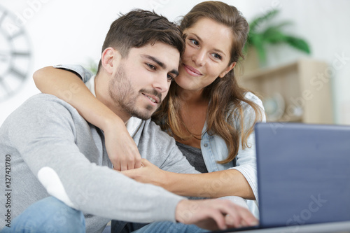 young man and woman smiling and browsing tablet and laptop