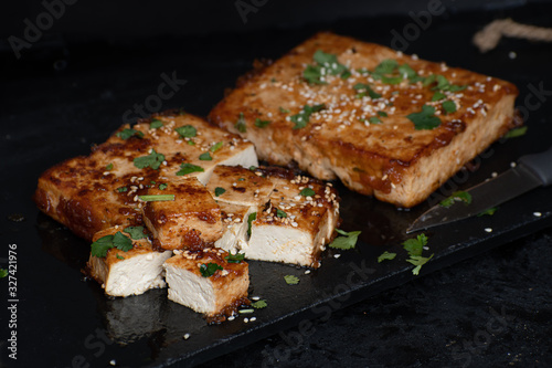 Teriyaki tofu steak slices on black slate