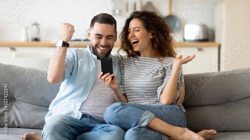 Excited young couple triumph reading news on cell photo