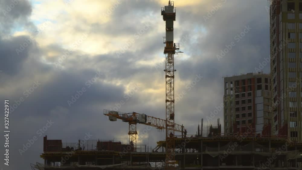 The work of construction cranes on the background of flying clouds The work of construction cranes on the background of flying clouds