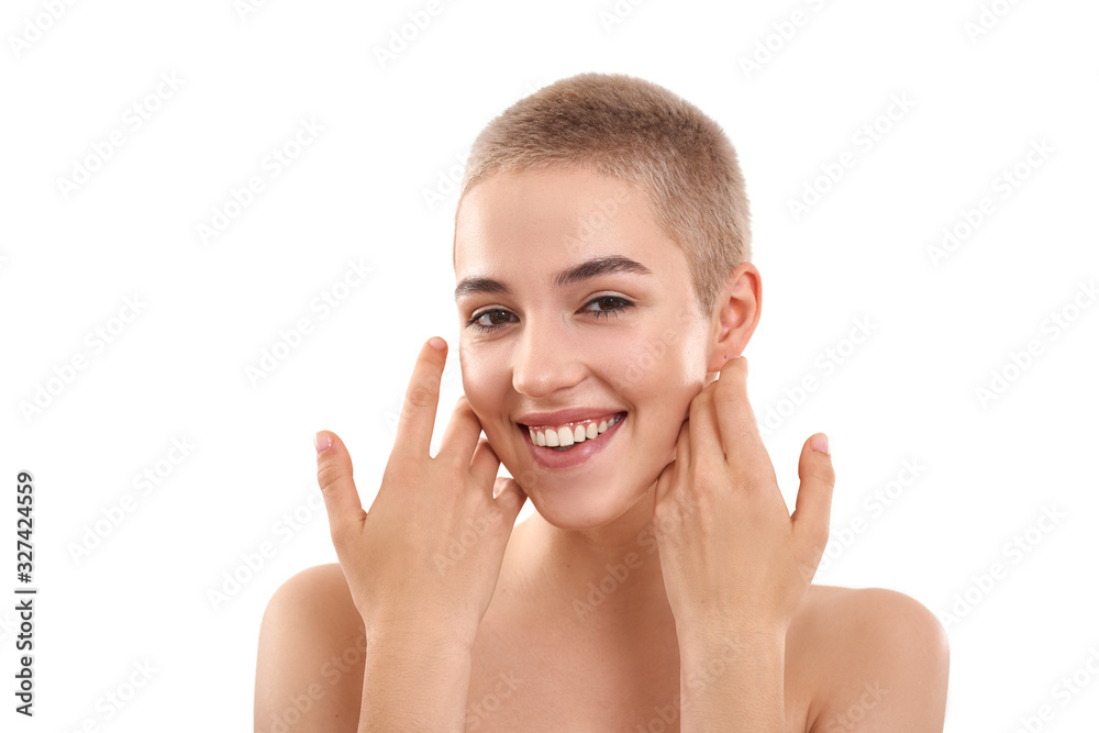 Glowing skin. Portrait of a beautiful smiling blond woman with short hair and nude make up touching her cheeks with hands and looking at camera Glowing skin. Portrait of a beautiful smiling blond woman with short hair and nude make up touching her cheeks with hands and looking at camera