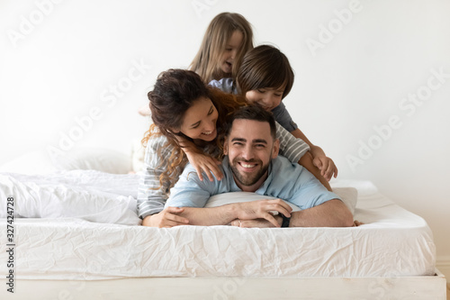 Happy young family with kids relax in bedroom