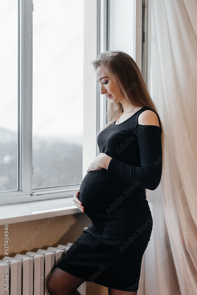 A pregnant girl is breathing fresh air from the window A pregnant girl is breathing fresh air from the window