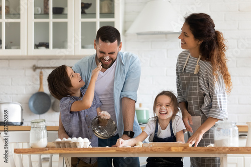 Canvas Print Overjoyed parents with little kids have fun cooking in kitchen