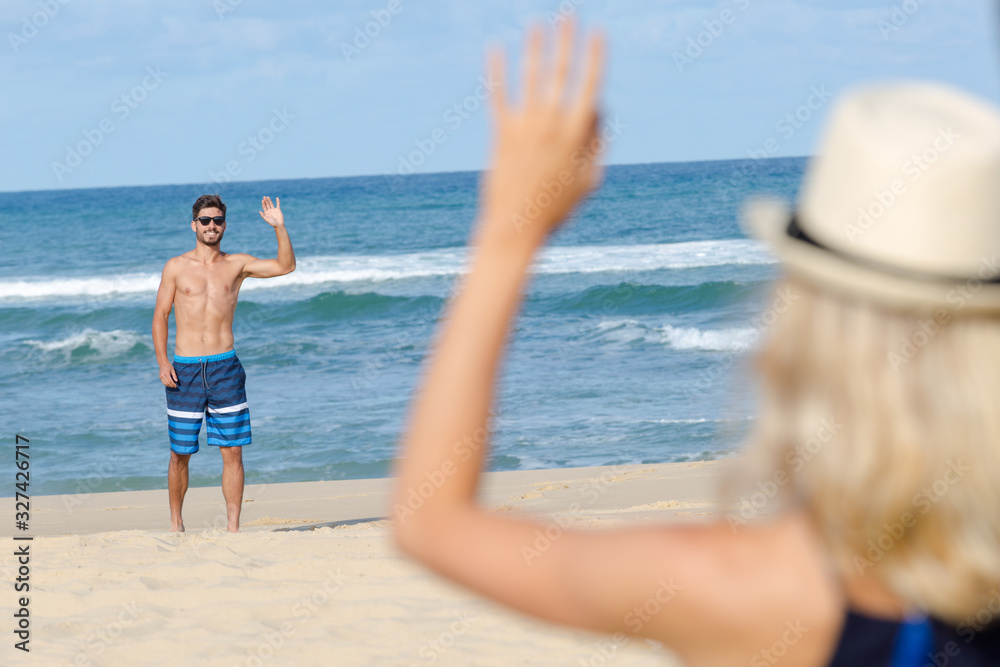 carefree young woman waving at boyfriend near the sea