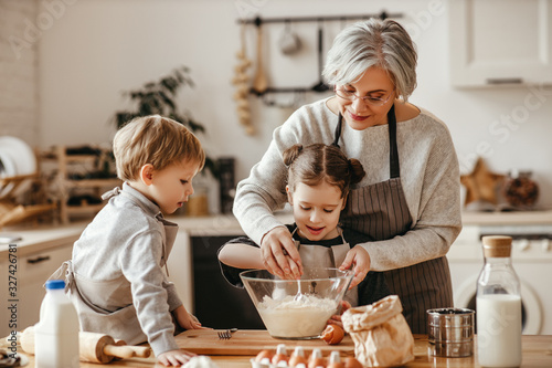 Foto happy family grandmother and grandchildren cook in the kitchen, knead dough, bake cookies