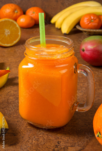 Mango orange banana and tangerine smoothie with ingredients on a brown background. Selected focus. photo