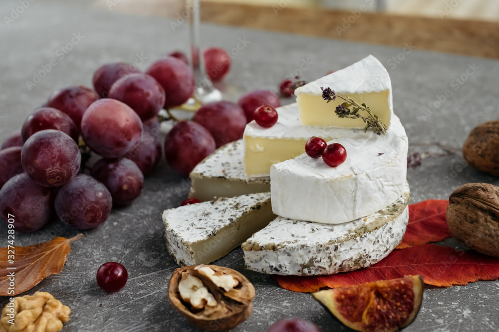 craft organic cheese (camembert, brie) with berries on concrete