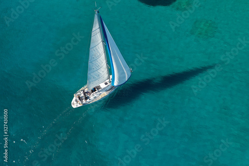Aerial drone photo of beautiful sail boat cruising in tropical exotic island bay resembling a blue lagoon © aerial-drone