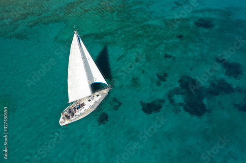 Aerial drone photo of beautiful sail boat cruising in tropical exotic island bay resembling a blue lagoon © aerial-drone