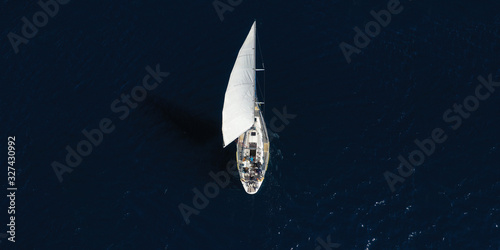 Aerial drone ultra wide photo of beautiful sail boat cruising in Aegean deep blue sea