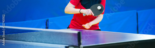 Ping pong table, woman playing table tennis with racket and ball in a sport hall