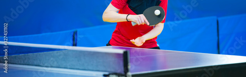 Tablou pe pânză Ping pong table, woman playing table tennis with racket and ball in a sport hall