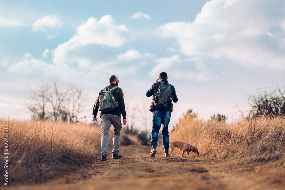 Fototapeta premium Two friends with a dog hiking together