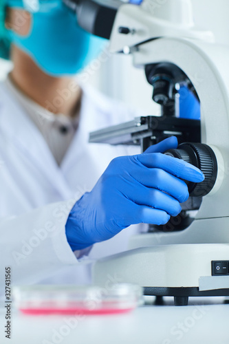 Close up of female scientist using microscope while working on research in medical laboratory