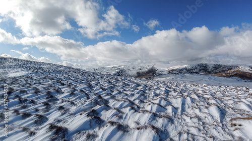 A scenic view of snowy mountain slope under a majestic blue sky and white clouds photo