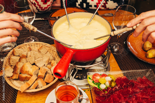 Friends eating cheese fondue in a cozy traditional swiss restaurant photo