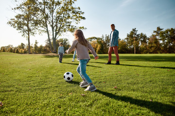 Get in the game. Happy family playing with a ball on meadow