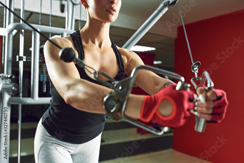 Athletic woman pumping up muscles on the simulator in the fitness room