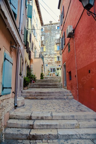 Vertical image of stairs in the Rovinj city mediterranean style alley with red building on the right side and orange on the left