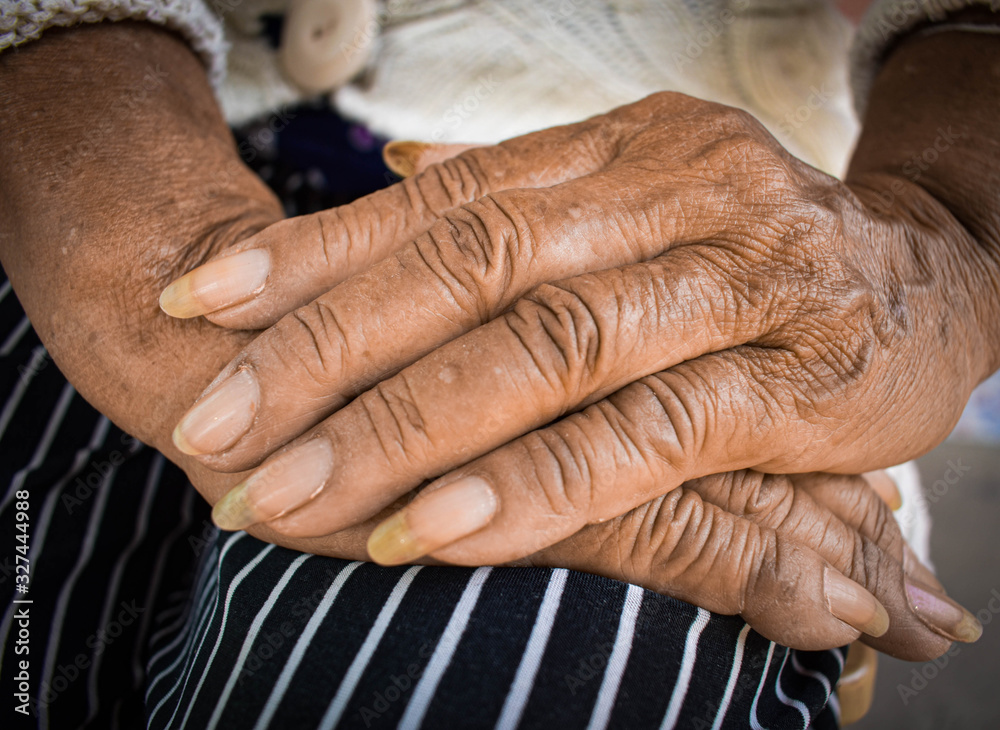 Fototapeta premium Old woman with wrinkles with clearly visible wrinkles, putting her hands on the lap