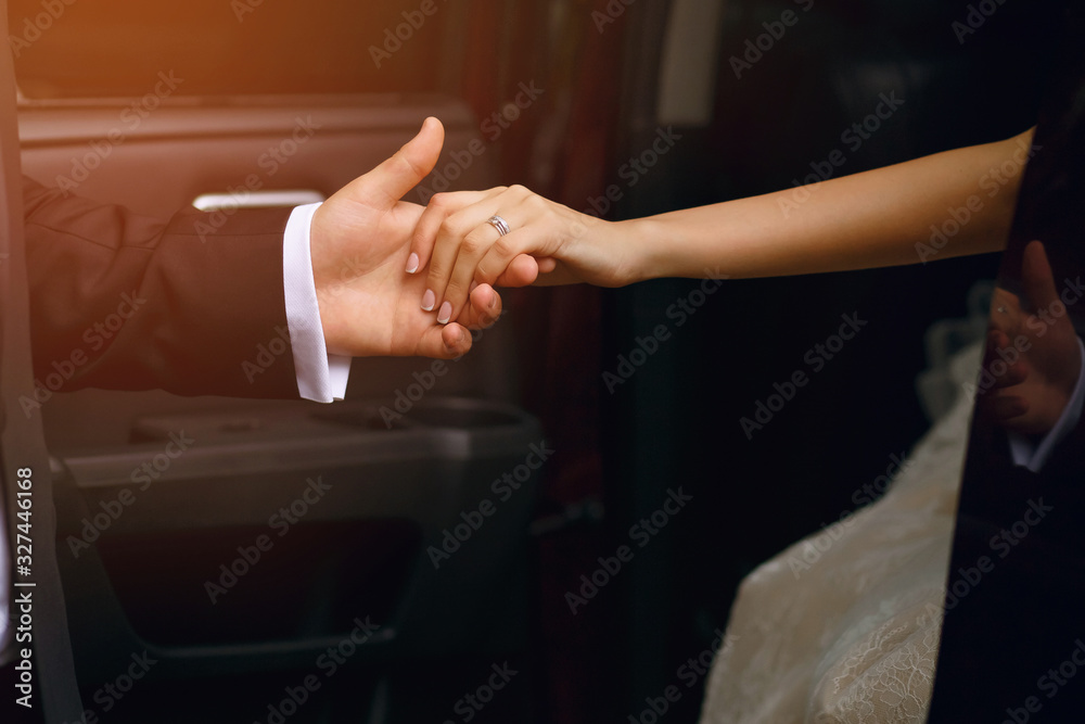 Bride and groom, a man holds out his hand to a woman when she gets out of the car