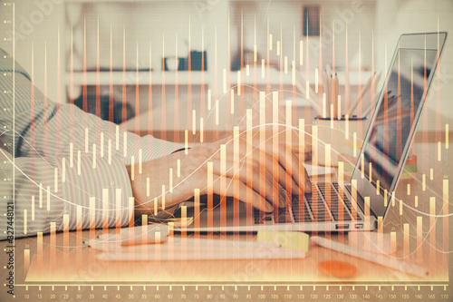 Double exposure of stock market graph with man working on laptop on background. Concept of financial analysis. © peshkova