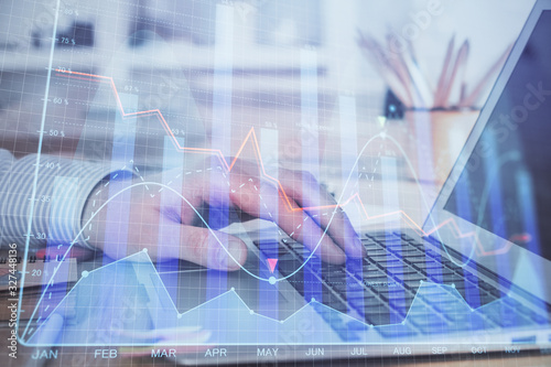 Double exposure of stock market graph with man working on laptop on background. Concept of financial analysis.