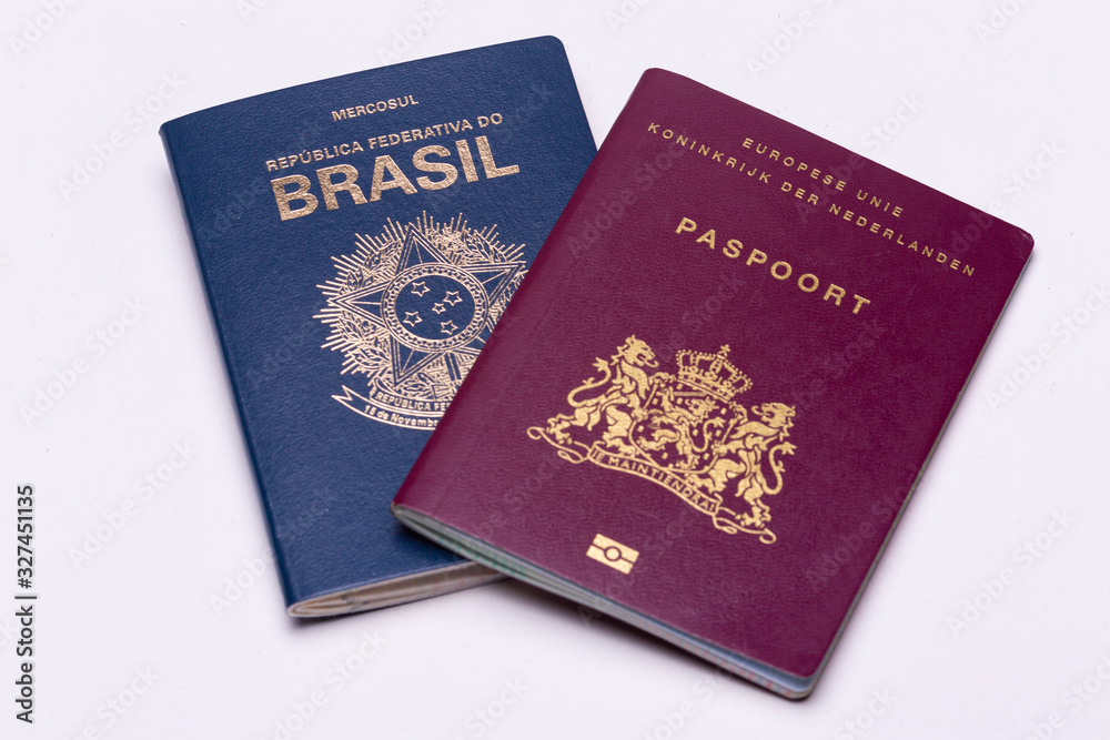 European - Dutch - on top of a Brazilian international passport a bright surface background. Concept double nationality. European - Dutch - on top of a Brazilian international passport a bright surface background. Concept double nationality.