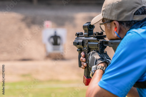 selective focus of man holding and fire sub machine gun to target in gun shooting competition