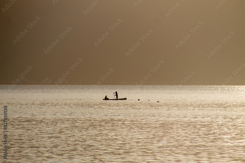 Fototapeta premium Two men on a boat fishing during the dawn