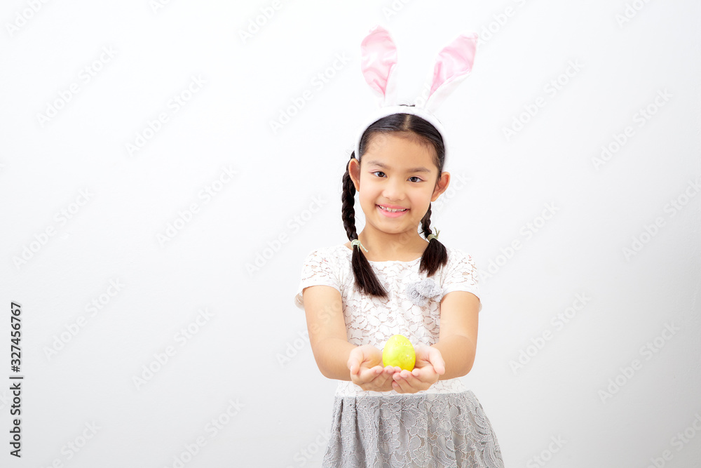 little child girl with easter bunny ears holding egg