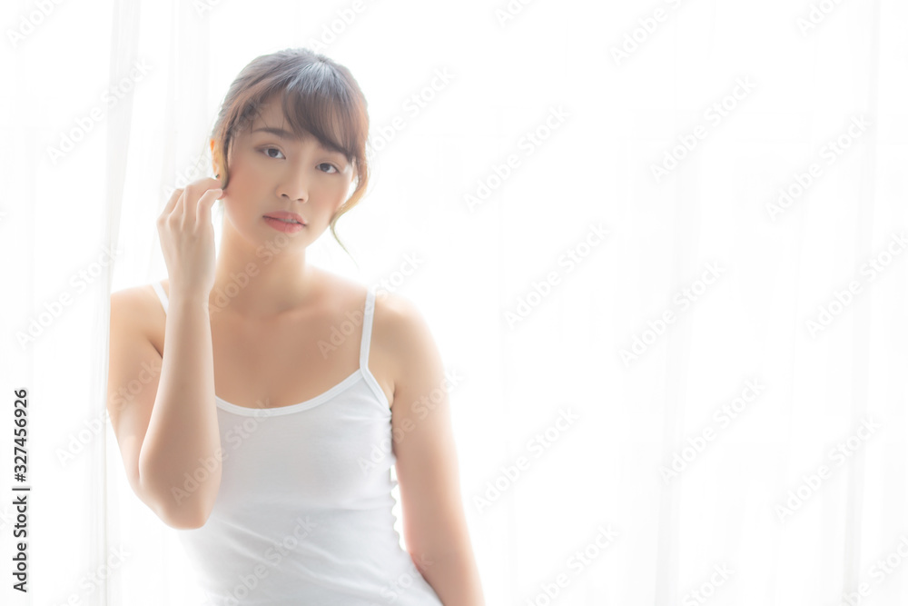 Portrait of beautiful young asian woman standing the window and smile while wake up with sunrise at morning, girl happy with freshness and cheerful, lifestyle and relax concept. Portrait of beautiful young asian woman standing the window and smile while wake up with sunrise at morning, girl happy with freshness and cheerful, lifestyle and relax concept.