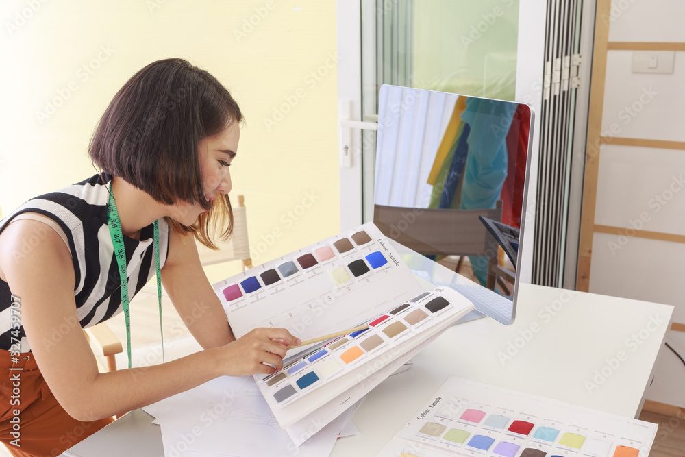 Beautiful Asian woman fashion designer holding pencil pointing sample color in workplace at home - Small business owner and SME concept