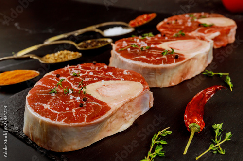 Fresh cut beef shank in bone and seasonings on black board.