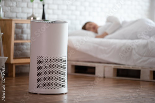 woman sleep with Air purifier in cozy white bed room for filter and cleaning removing dust PM2.5 HEPA in home,for fresh air and healthy life,Air Pollution Concept photo